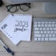 2023 goals written on tablet surrounded by a pen, glasses, keyboard
